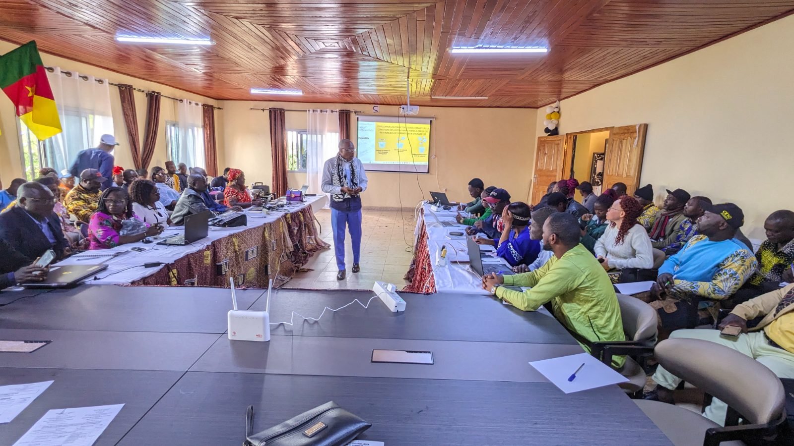 Devant l’écran qui affiche « Développer les compétences des formateurs à concevoir des leçons impactantes à partir des référentiels de formation en utilisant l’IA », un intervenant s’adresse aux participants.