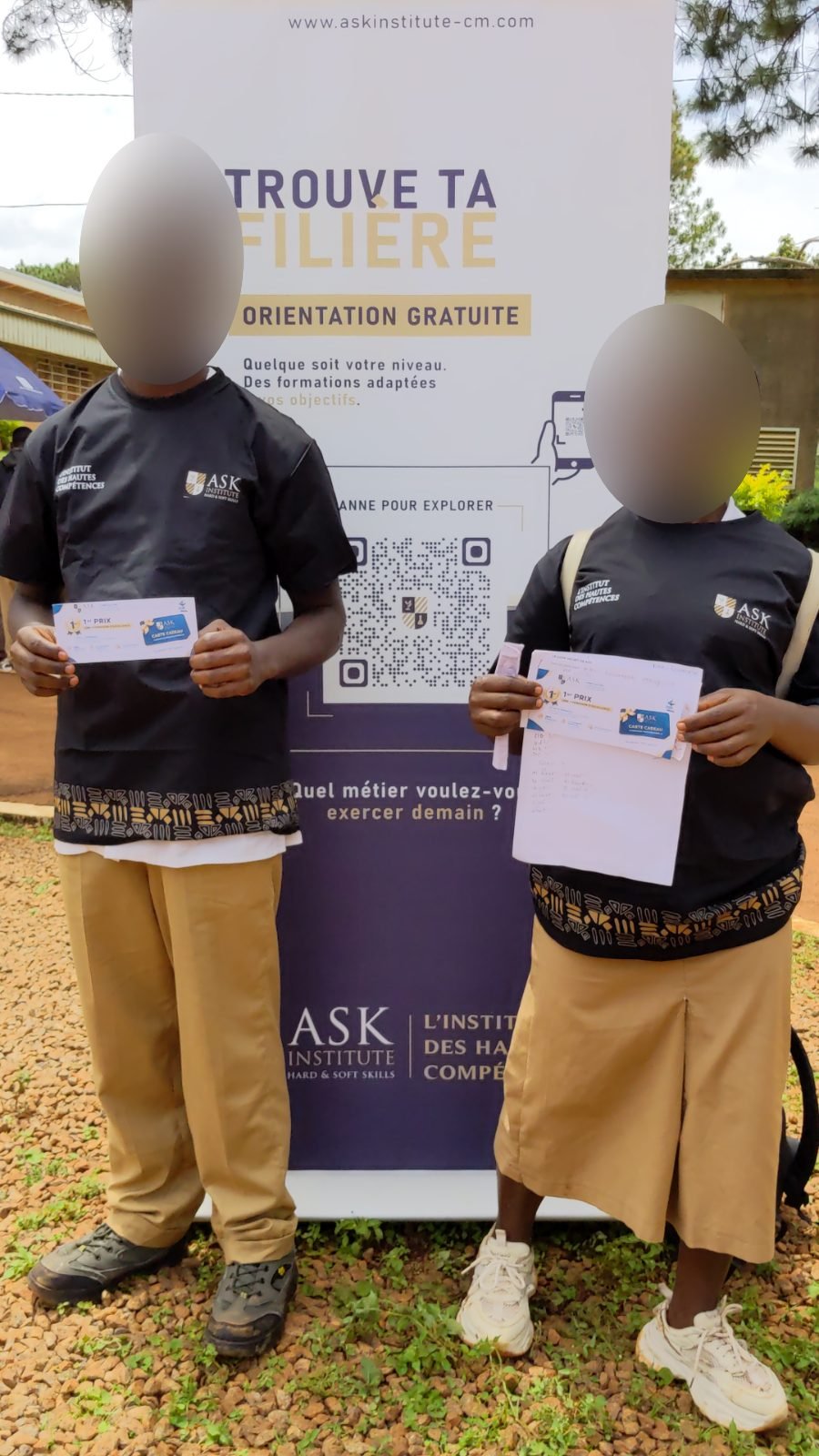 Deux élèves vêtus du tee-shirt de ASK Institute présentent leur carte cadeau « 1er prix » devant le kakémono « Trouve ta spécialité, orientation gratuite ».