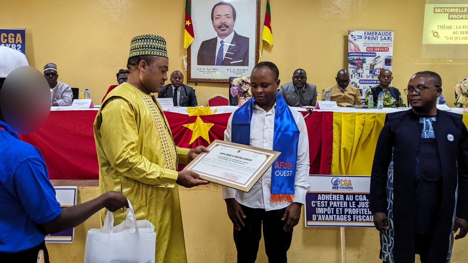 Remise d’un diplôme d’excellence à un lauréat portant l’écharpe AFOP-OUEST, devant la table officielle.