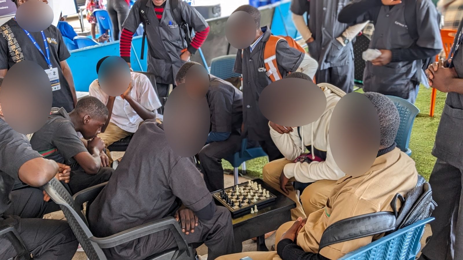 Des jeunes visiteurs disputent une partie d’échecs sur le stand de ASK, entourés de spectateurs attentifs.