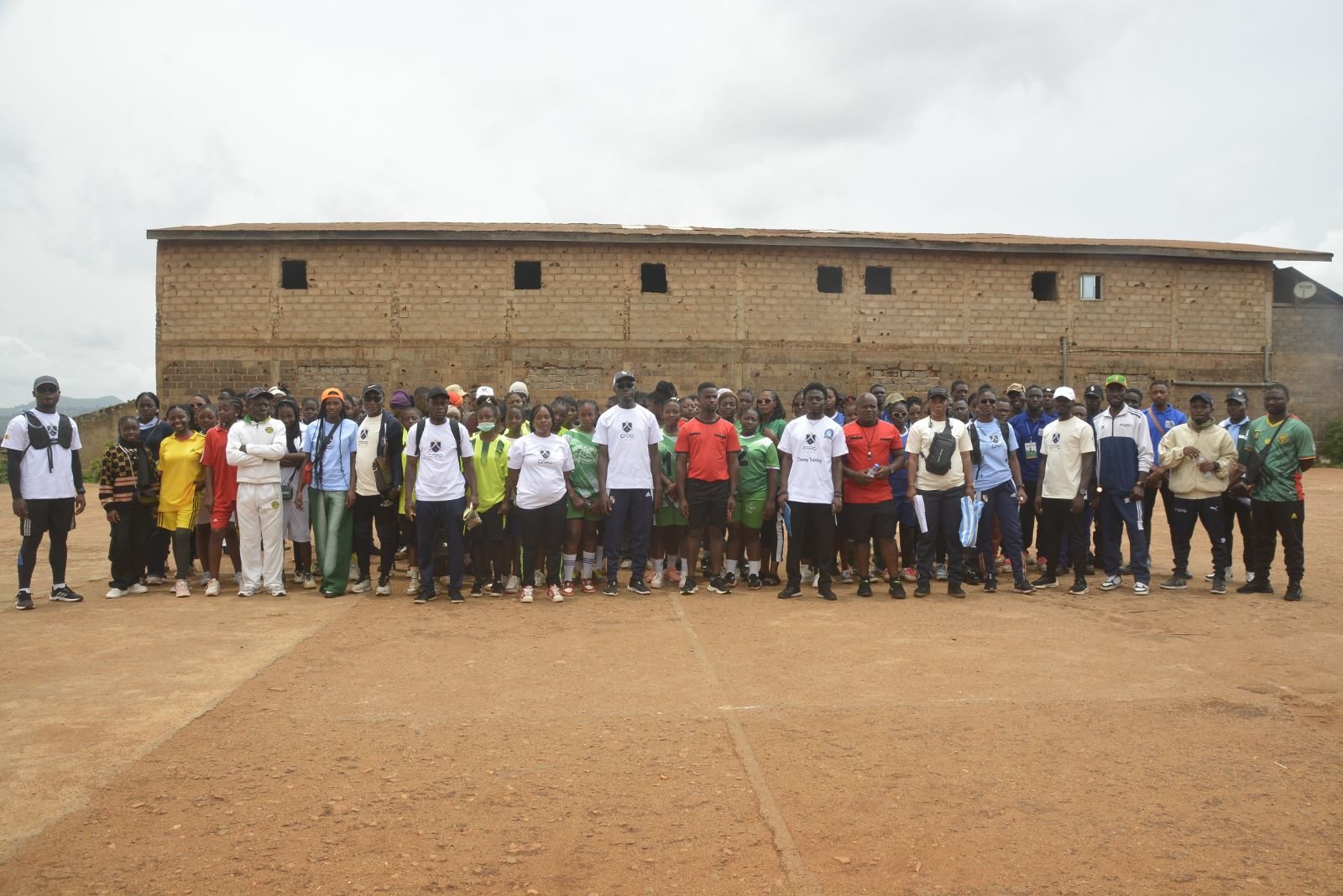 Photo de groupe des participants, alignés sur le terrain de handball.